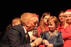 Co-host Adam Tomlinson interviews one small child ons tage at the Carol Concert.jpg